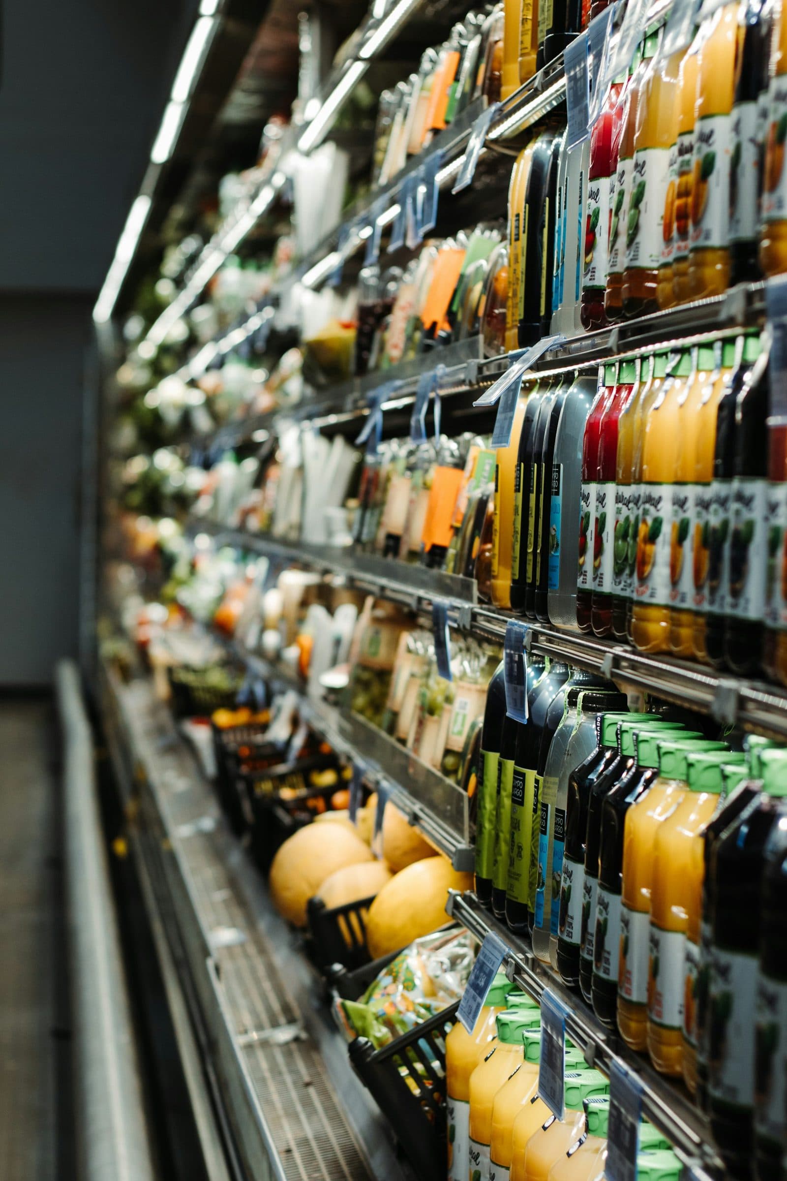 A long chilled aisle of drinks and fresh produce in a supermarket